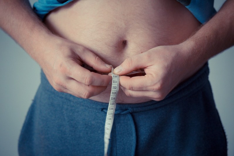 Man measuring his stomach with measuring tape