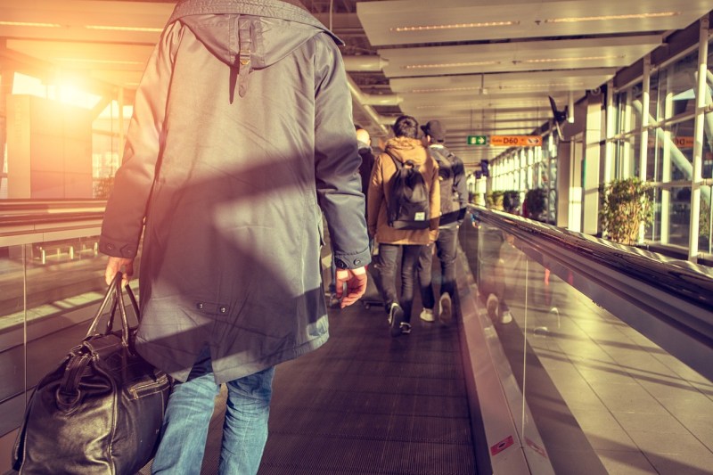 The back of a passenger on a moving sidewalk in an airport