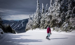 Snowboarder riding down trail at Smuggler's Notch