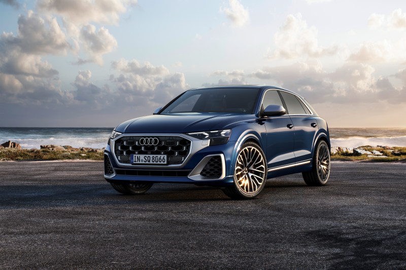 2024 Audi S Q8 in Waitomo Blue left front three-quarter view on pavement near the ocean shore - European Model Shown..