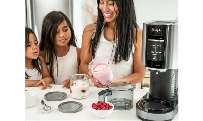A family using the Ninja Creami Ice Cream Maker on their kitchen counter.