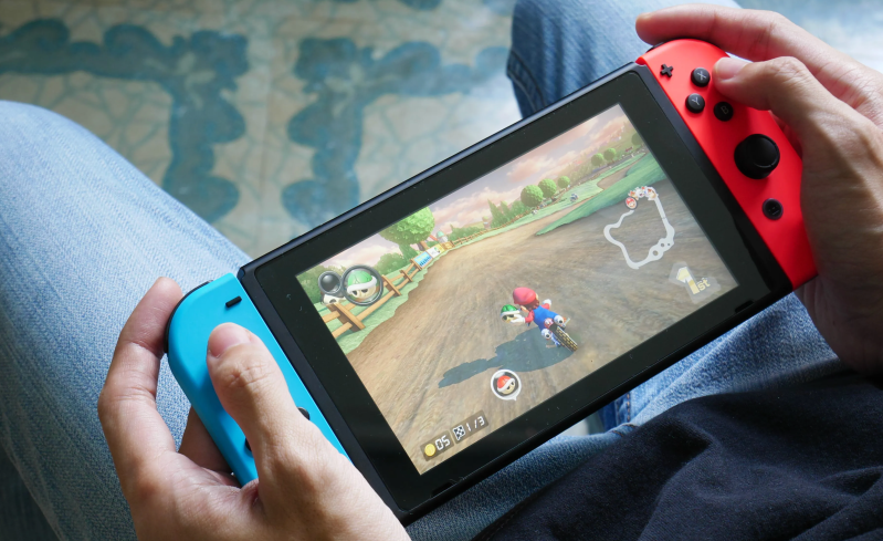 A person plays Mario Kart 8 Deluxe on a Nintendo Switch in handheld mode.