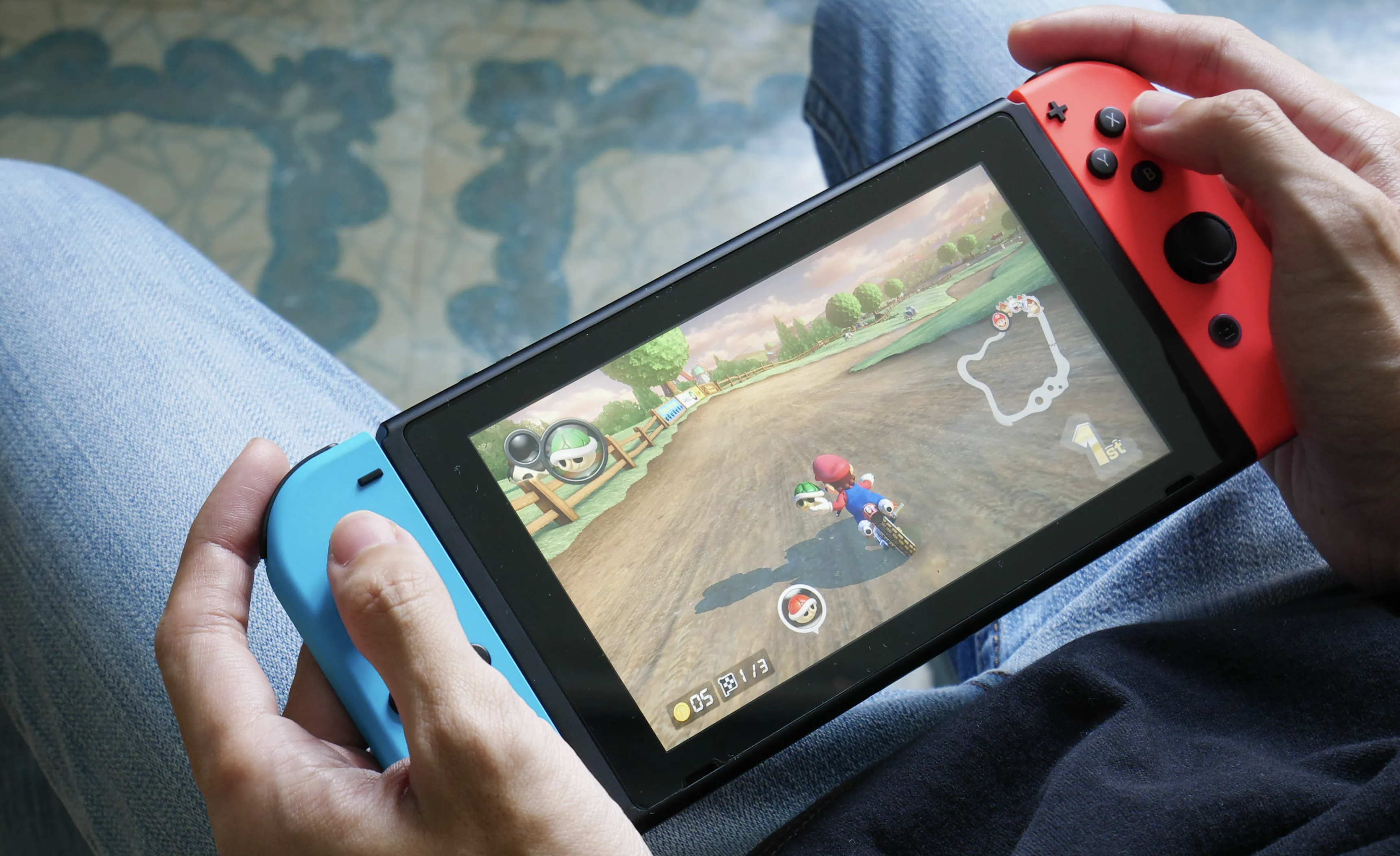 A person plays Mario Kart 8 Deluxe on a Nintendo Switch in handheld mode.