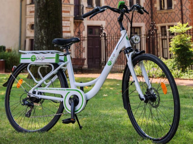 Pi-Pop battery-less electric bike parked on grass in front of a brick building.