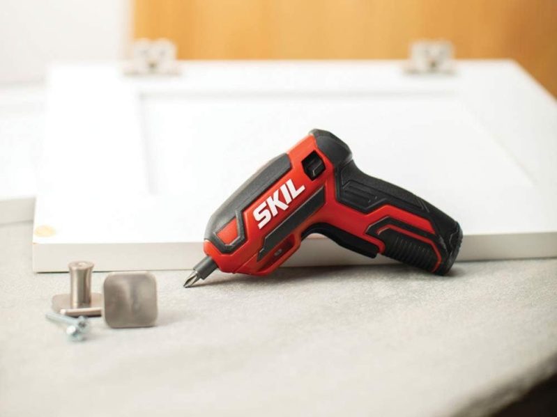 A Skil 4V rechargeable cordless screwdriver sitting next to screws and other small objects.