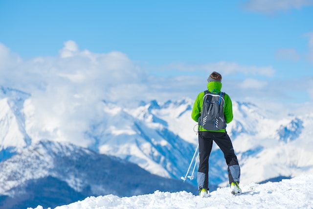 Man standing on a snowy hill trail taking in the view while cross country skiing