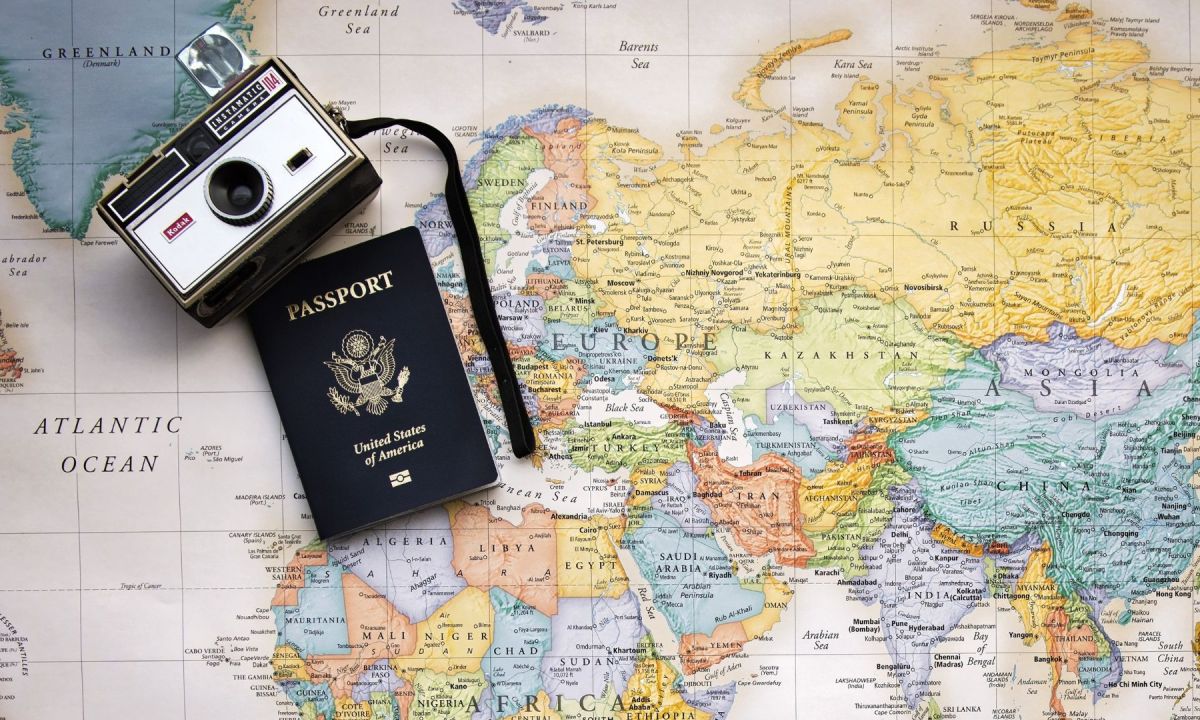 Passport and vintage camera on a world map