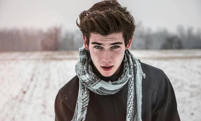 Man standing in cold with scarf. and hair blowing in wind