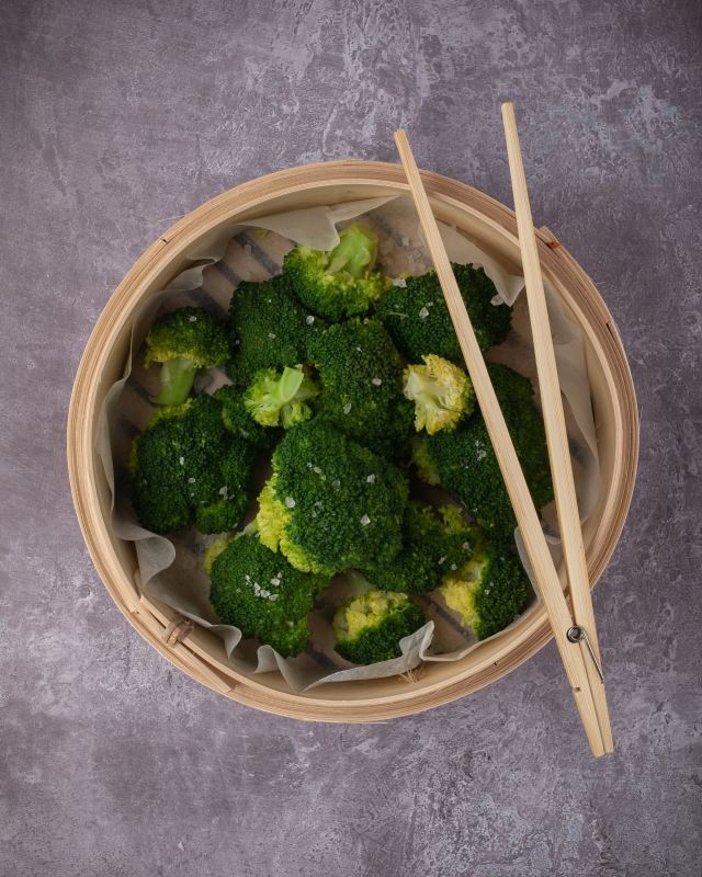 Broccoli in a beige ceramic bowl with chopsticks