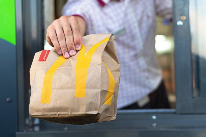 Hand with a paper bag through the window of McDonald's drive-thru