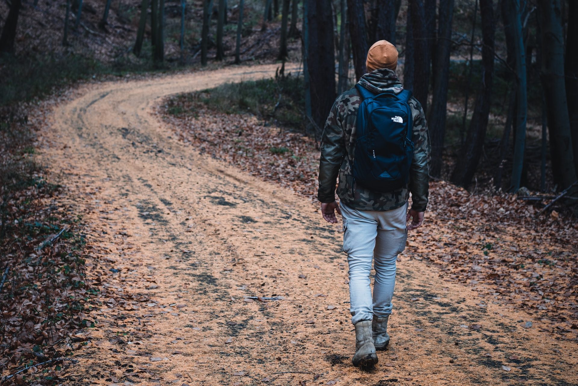 A man in a hat walking along a winding hiking trail