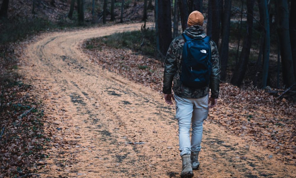 Man wearing hat walking through winding hiking trail