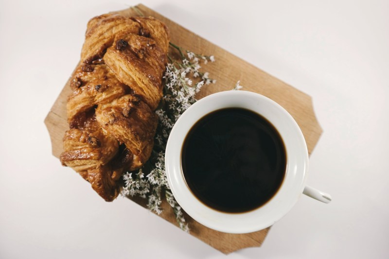 Black cup of coffee next to a pastry