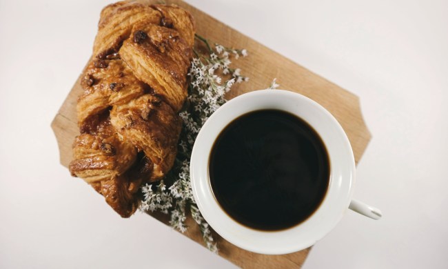 Black cup of coffee next to a pastry