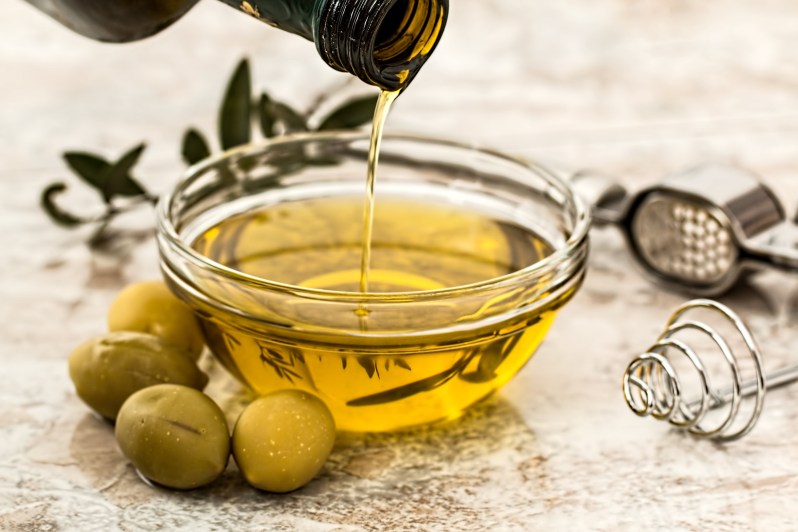 Olive oil being poured into glass jar