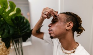 Man applying serum in mirror during skincare routine