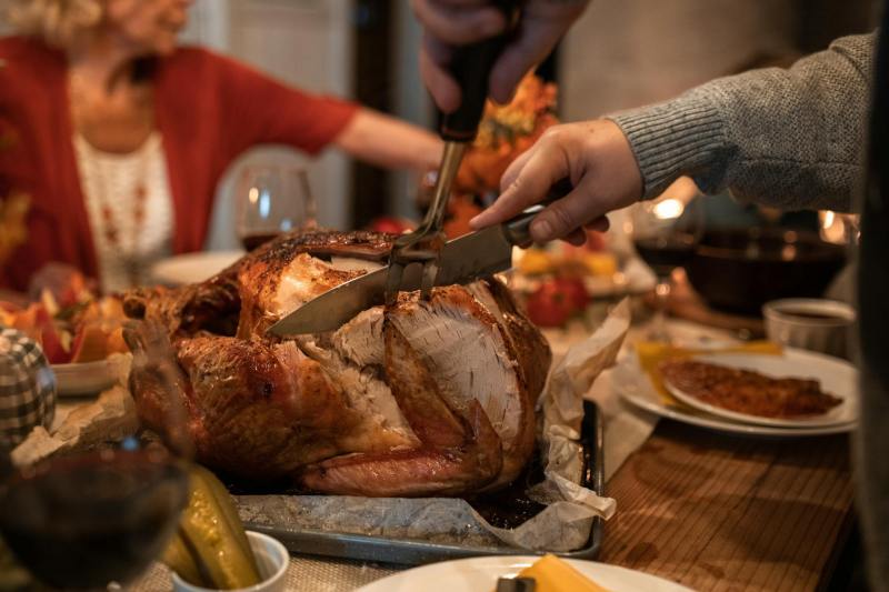 Person carving turkey at Thanksgiving table