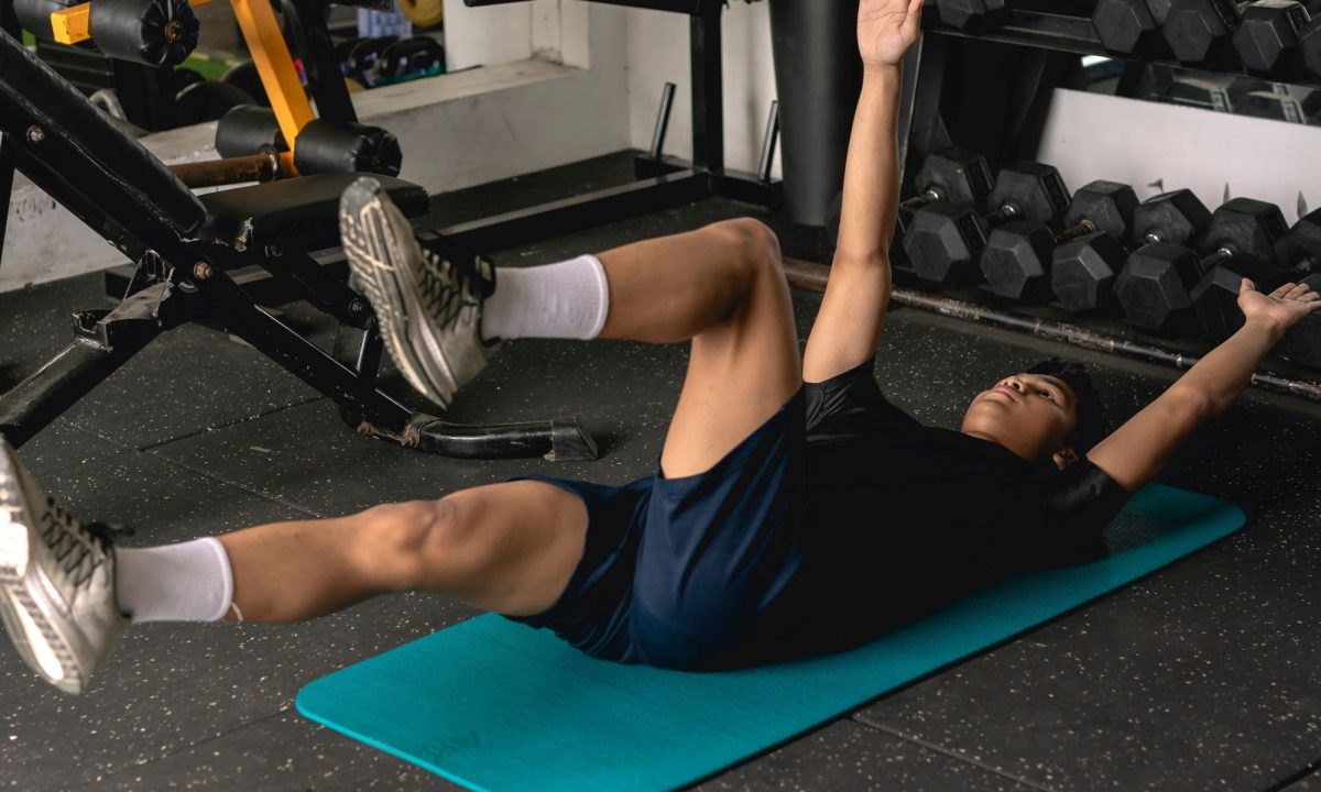 Man doing dead bug exercise on floor on blue mat