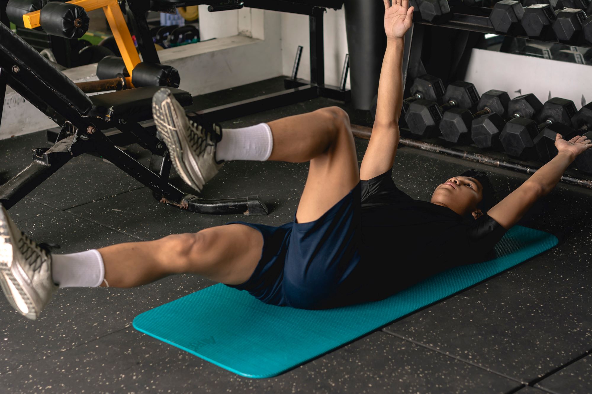 Man doing dead bug exercise on floor on blue mat