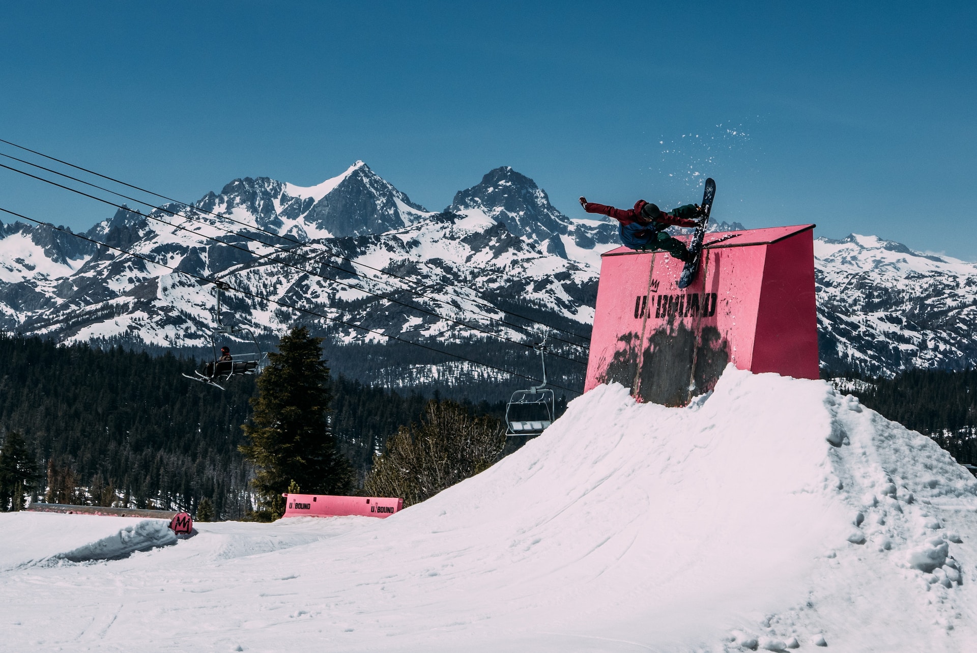 A snowboarder hits a park feature on their freestyle snowboard.