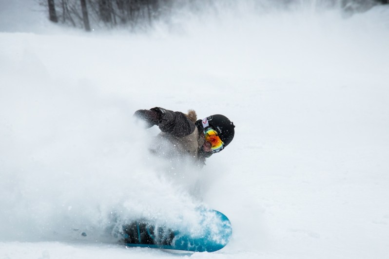 Snowboarding riding powder with red goggles