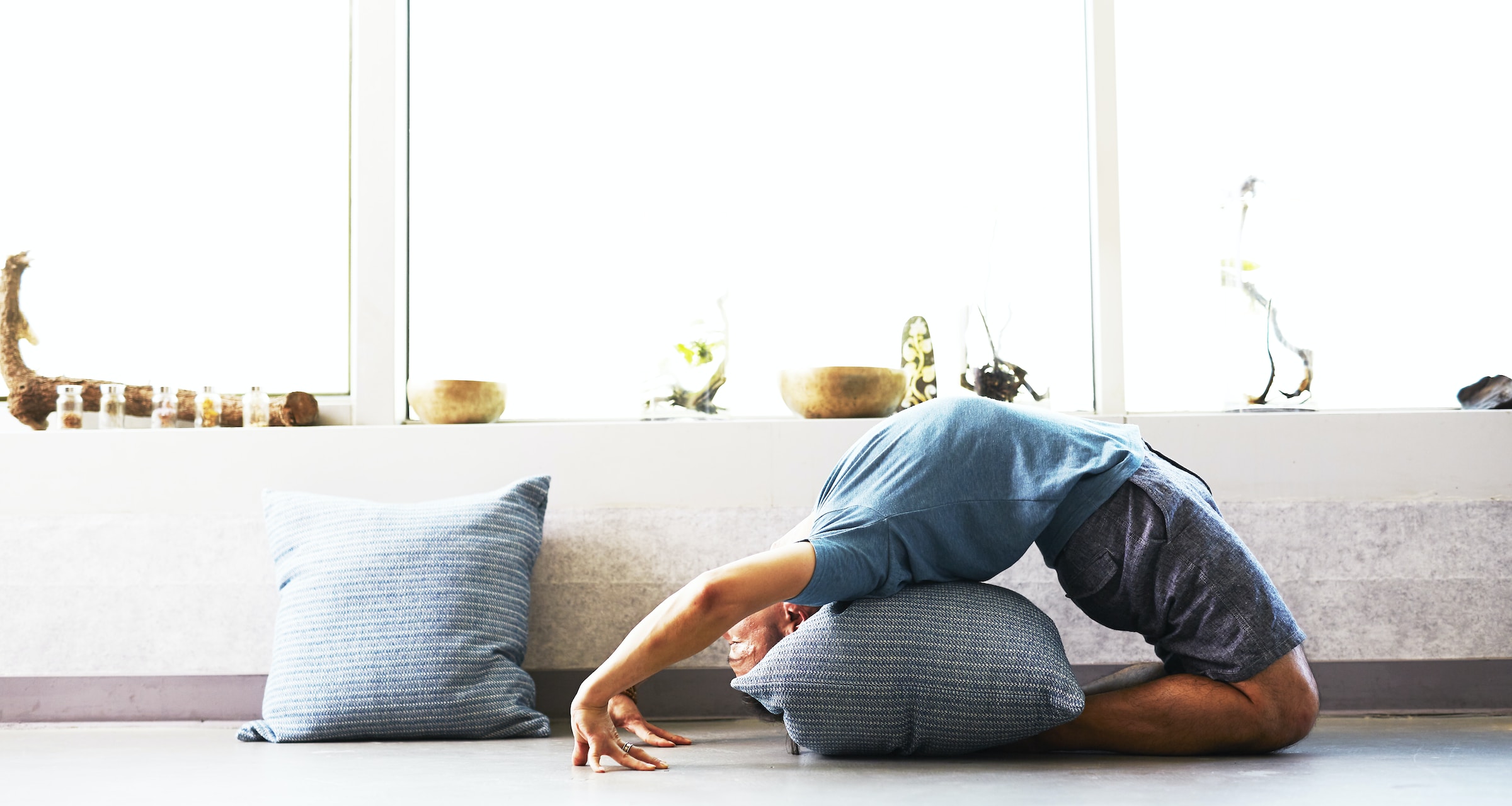 man doing yoga pose backward bend over pillow at home