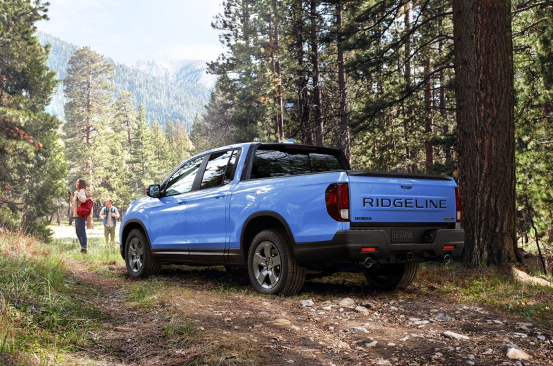 2024 Honda Ridgeline TrailSport parked on a road in a forest with two people walking away.