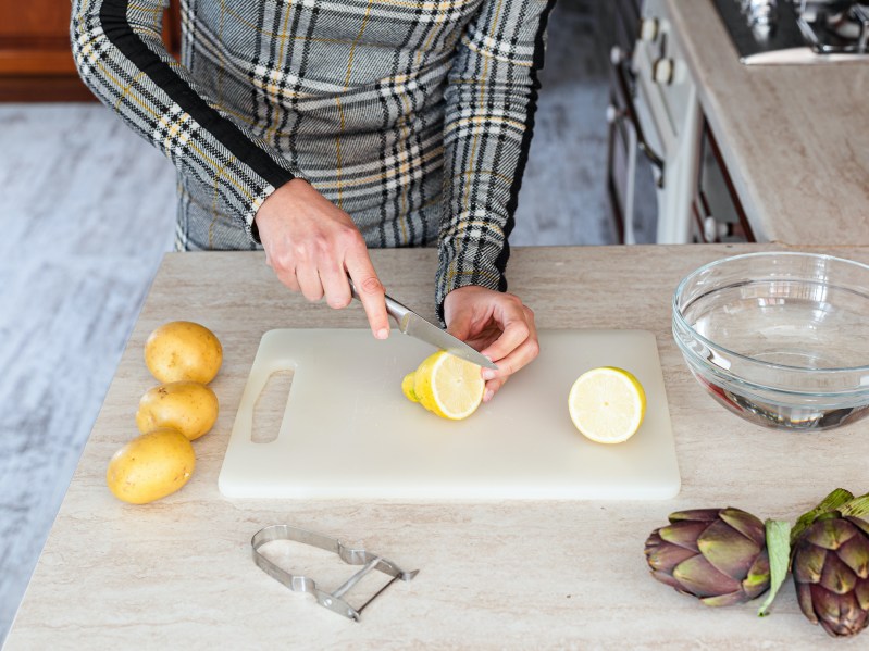 Person cutting lemons on plastic cutting board