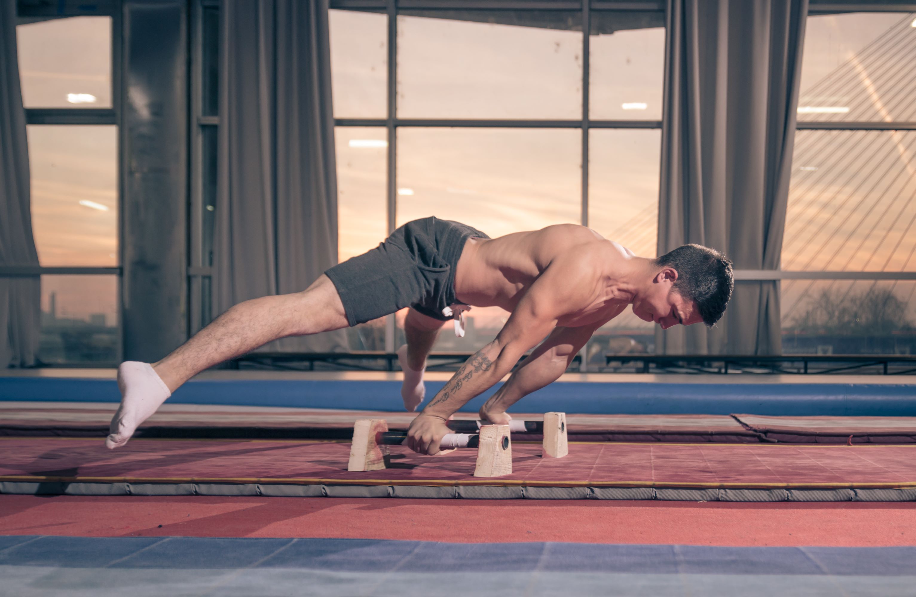Man wearing shorts, no shirt, exercising with bar, gymnastics
