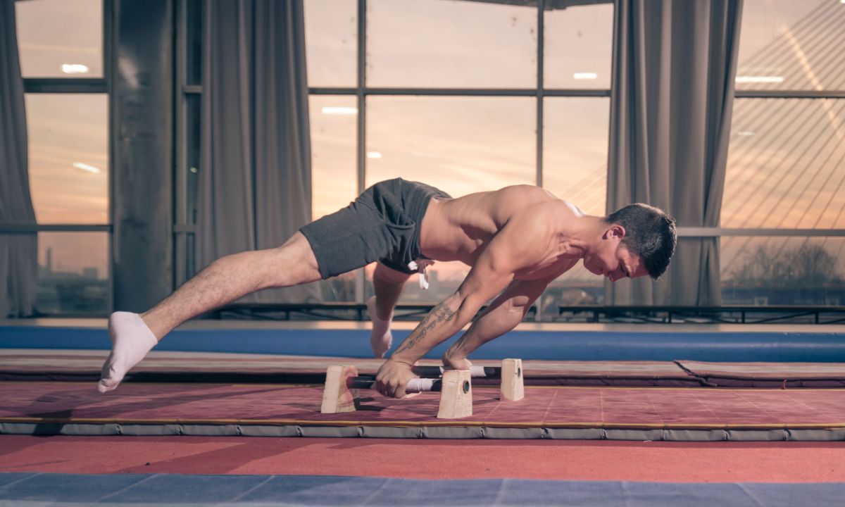 Man wearing shorts and no shirt working out exercising on bars calisthenics
