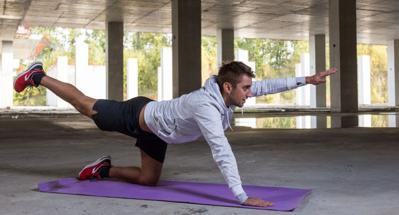 Man doing bird dog plank on purple mat