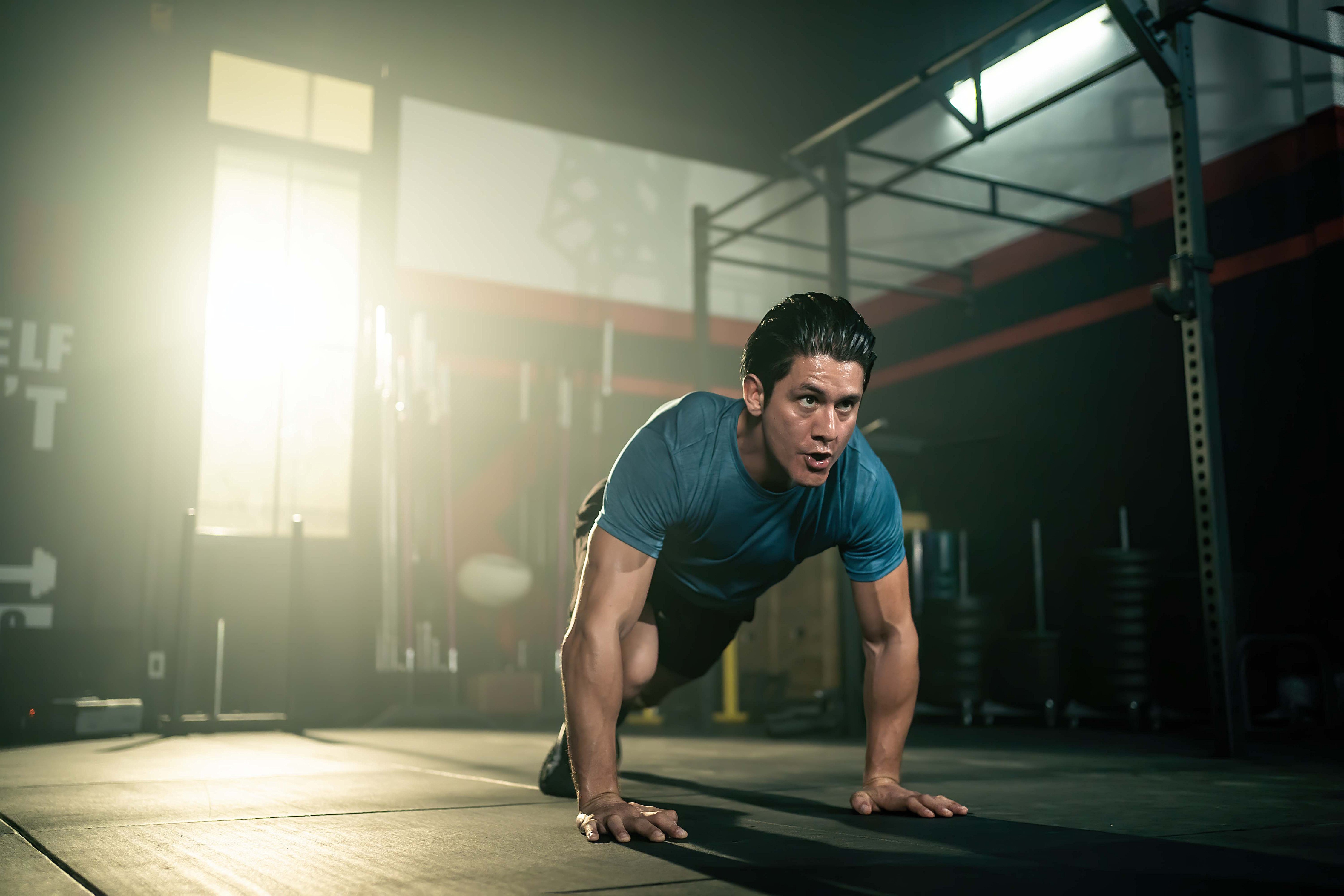 man doing pilates on mat on floor running pose wearing blue shirt