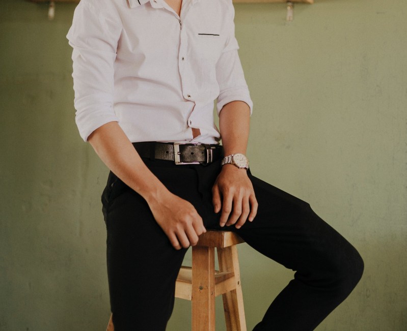 man wearing belt and watch sitting on stool