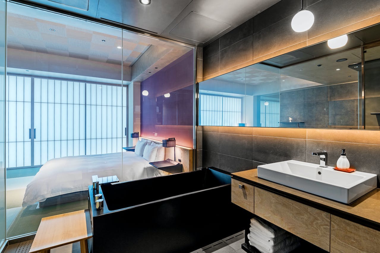 Interior of a hotel room with a bed, bathtub, and sink in one room.