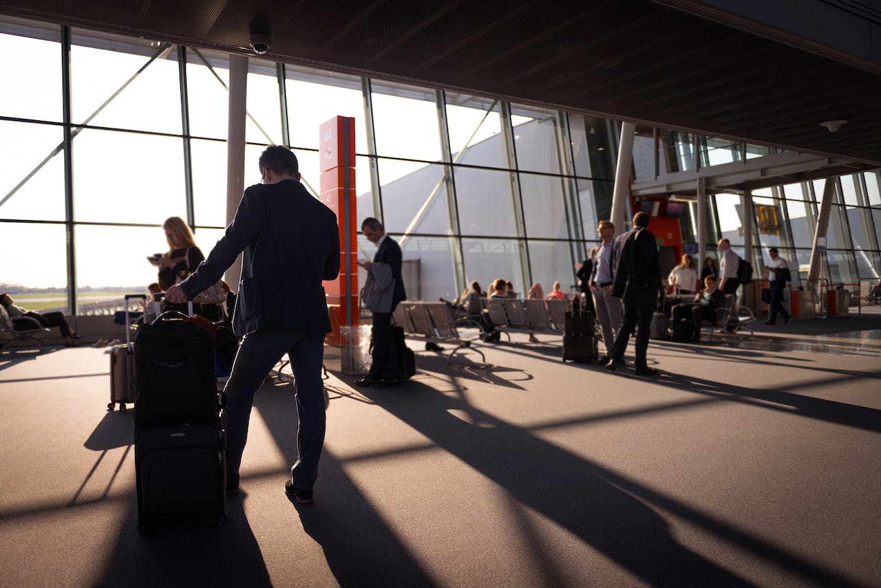 Interior of an airport with people stanidng in the shadows in front of a window