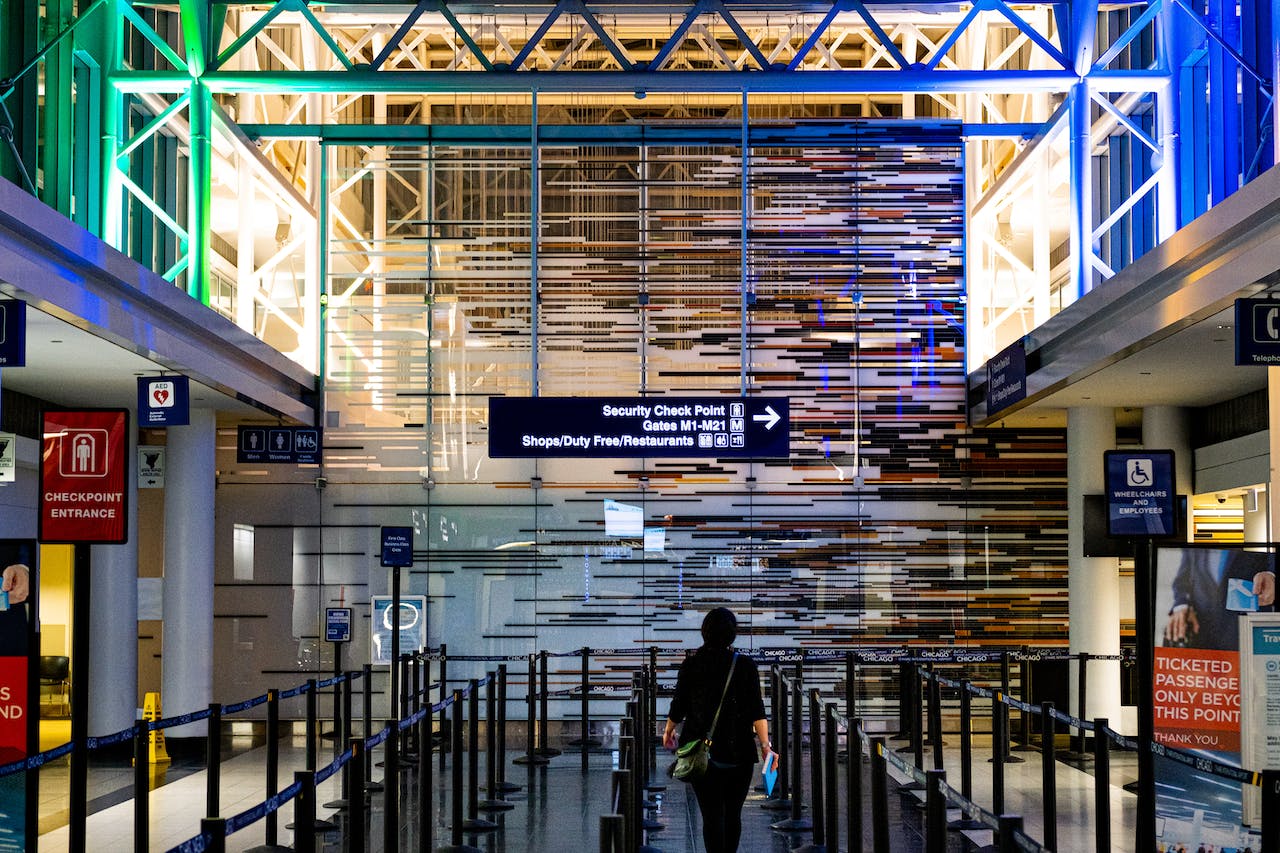 A person standing before an airport security sign, as pictured from the back