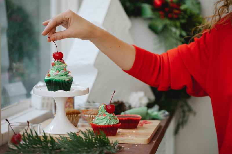 Person decorating Christmas cupcakes
