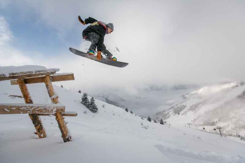 Snowboarder jumping over a picnic table
