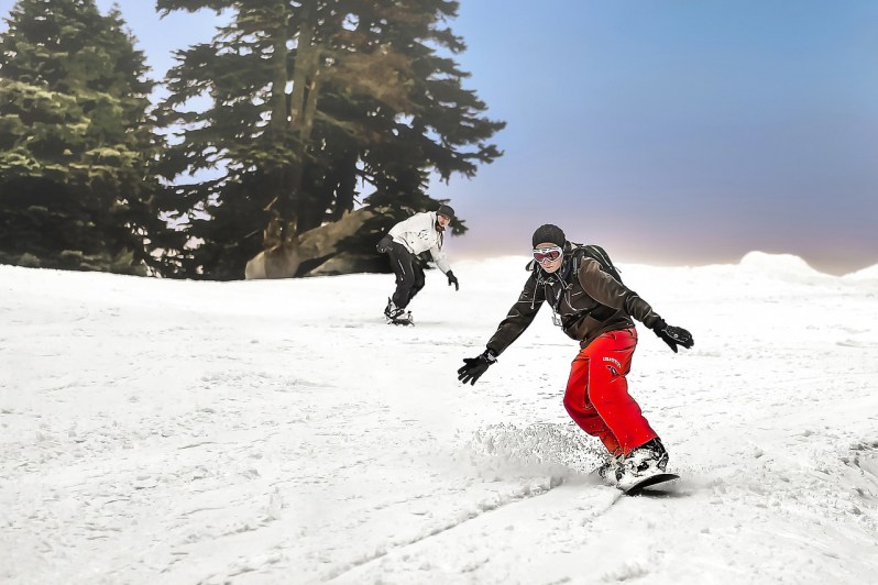 Snowboarders riding through powder