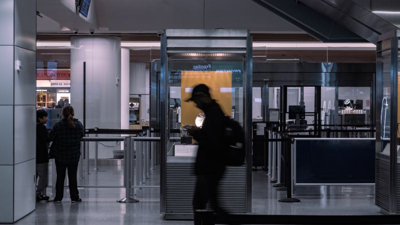 A man walking past an airport security station in motion
