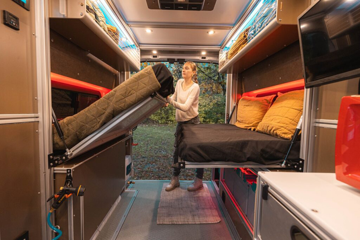 Woman folding up "drawbridge-style" bed in the Vandoit Moov camper van.