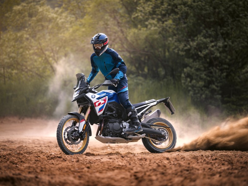 Rider standing driving 2024 BMW F 900 GS in dirt.