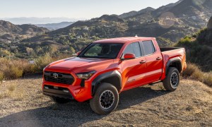 2024 Toyota Tacoma i-Force Max hybrid pickup parked on a hill with mountains and desert in the background