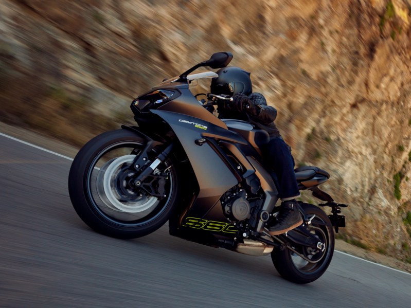 2024 Triumph Daytona 660 driving on pavement through a canyon viewed from the left side.