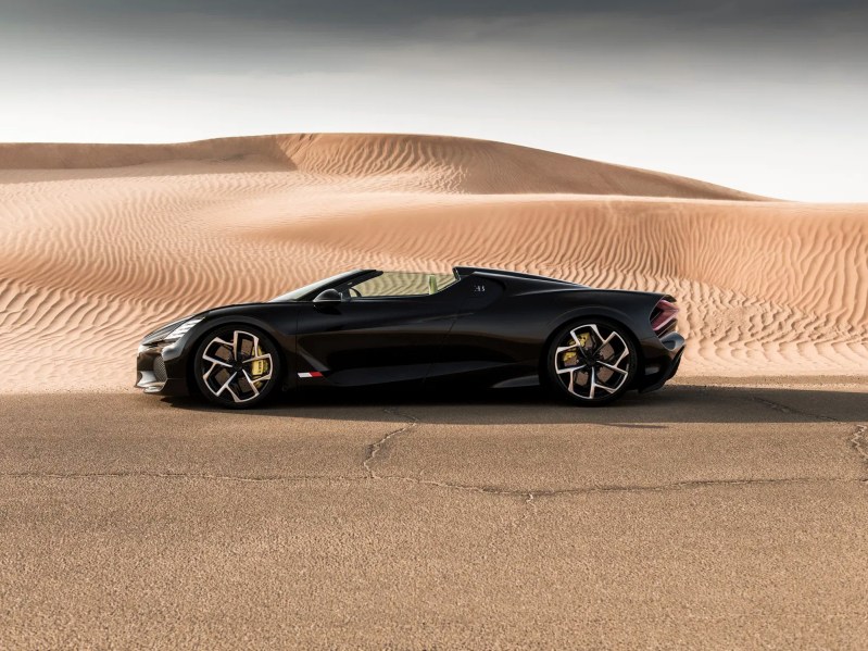 Black Bugatii W16 Mistral parked facing left side view with desert dunes in the background.
