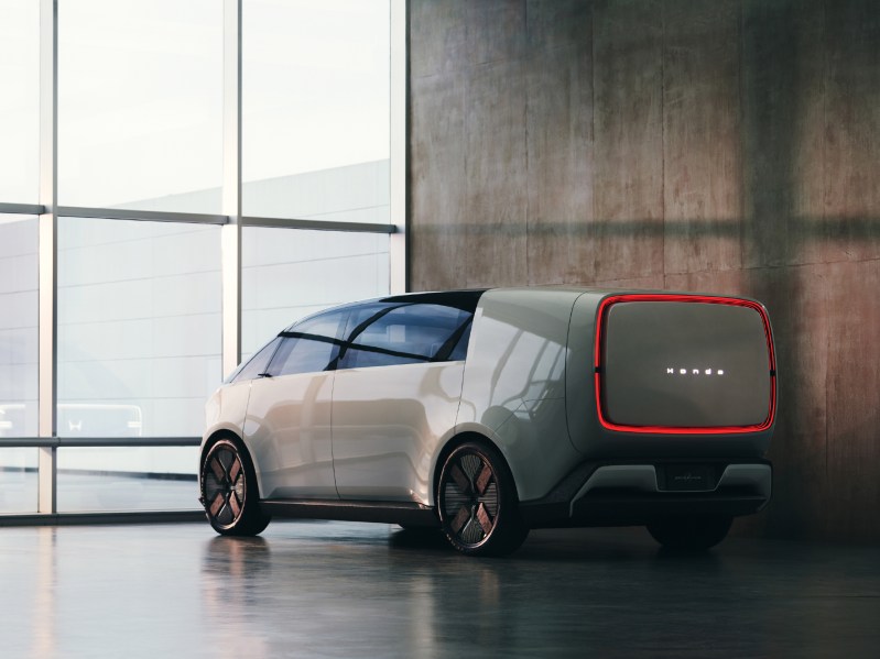 Honda 0 Space-Hub concept EV left rear three-quarter view parked inside a gleaming floor with a wooden wall on the right side and a wall of glass on the left.