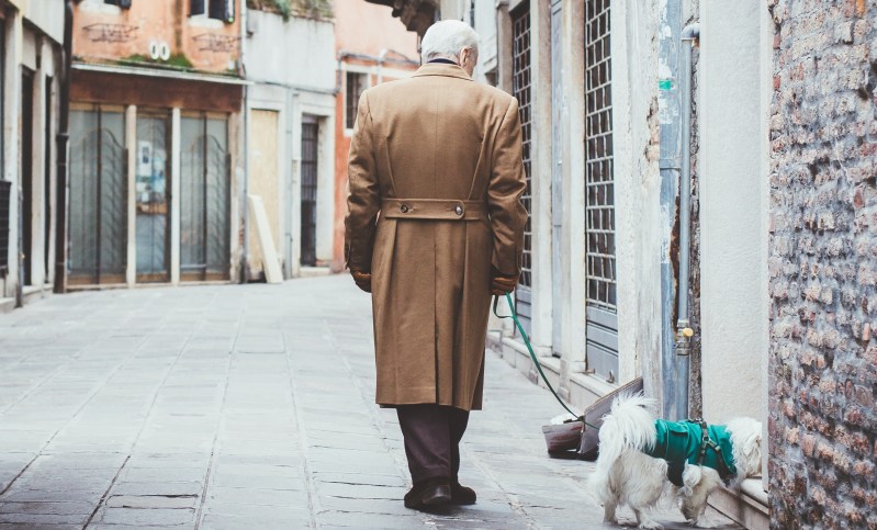 Man in trench coat walking a dog