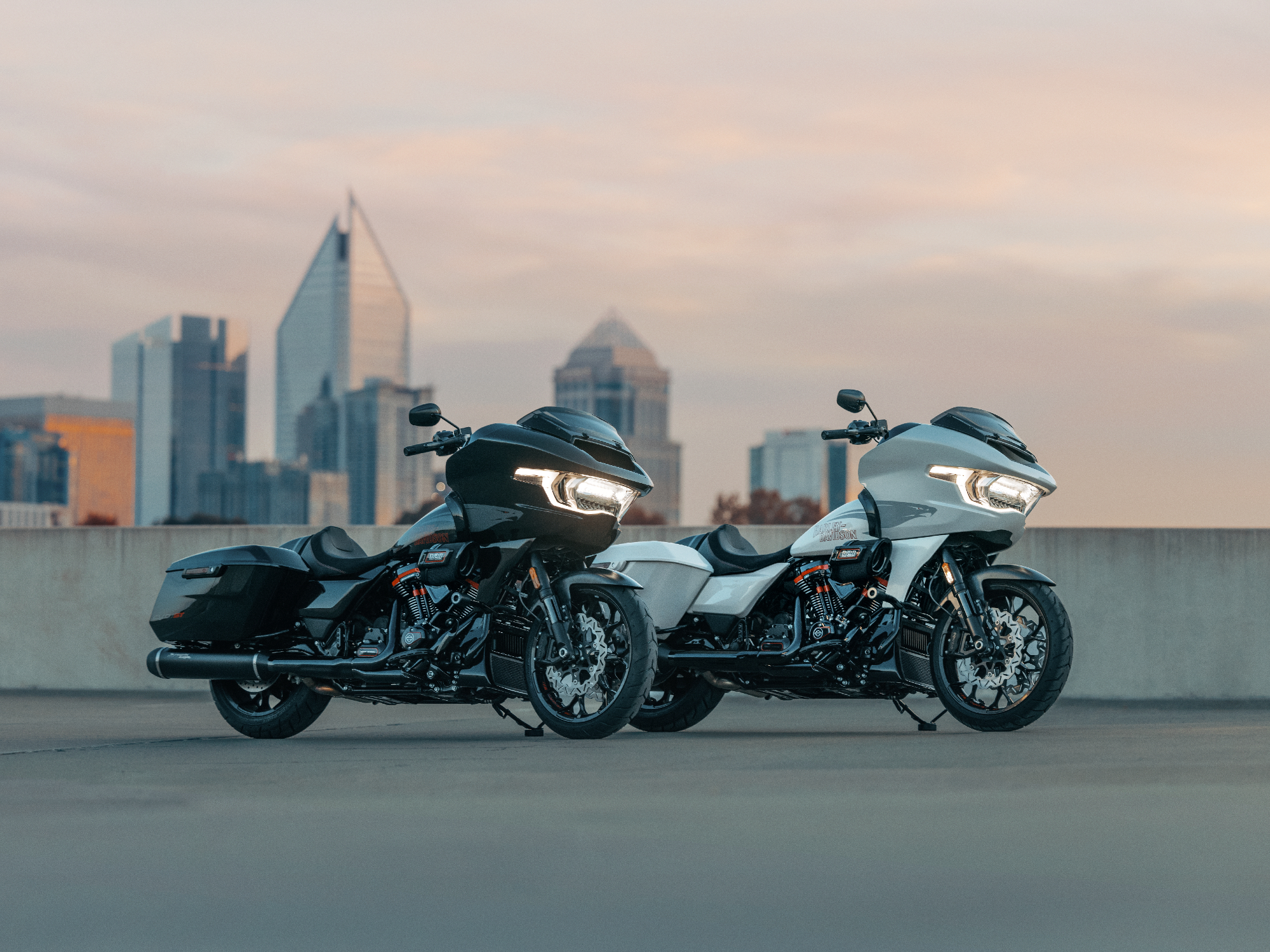 Two 2024 Harley-Davidson CVO Road Glide STs parked on a concrete deck overlooking a city.