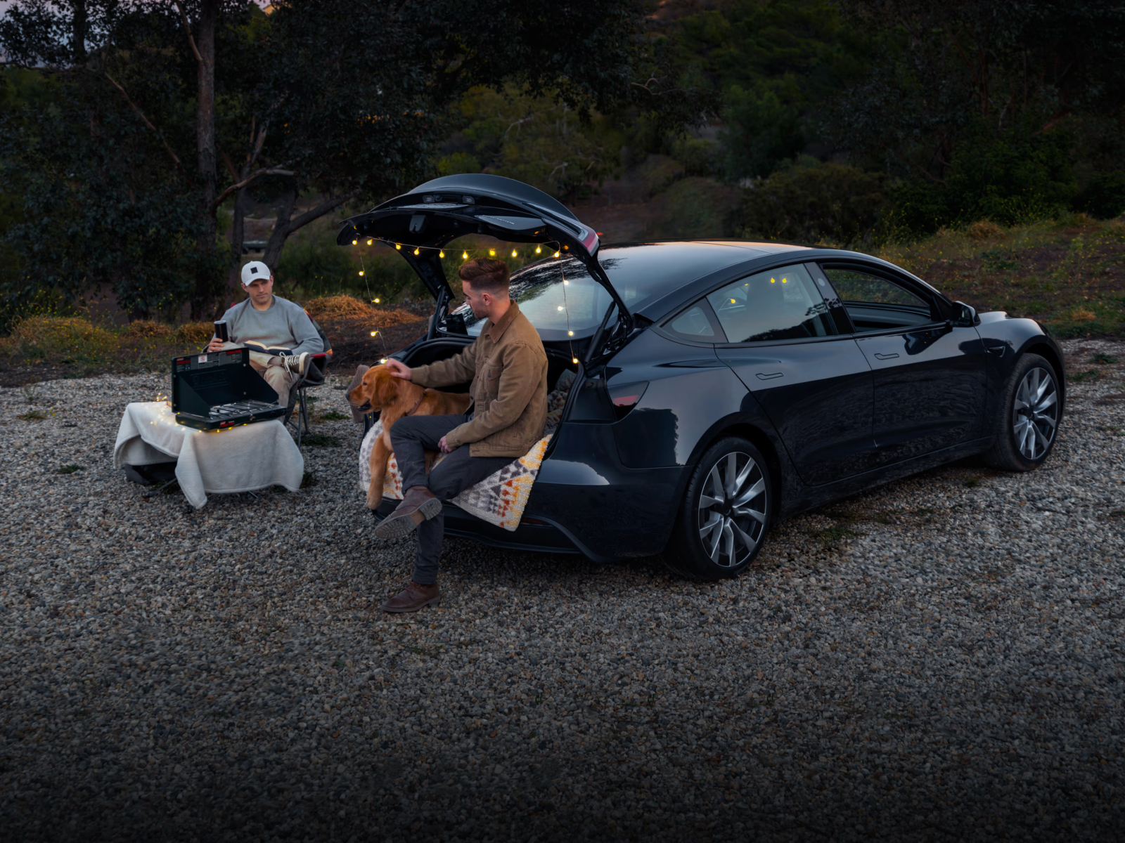 tesla model 3 refresh two people and a dog parked on gravel with in camp mode to keep cabin temperature level entertainment s