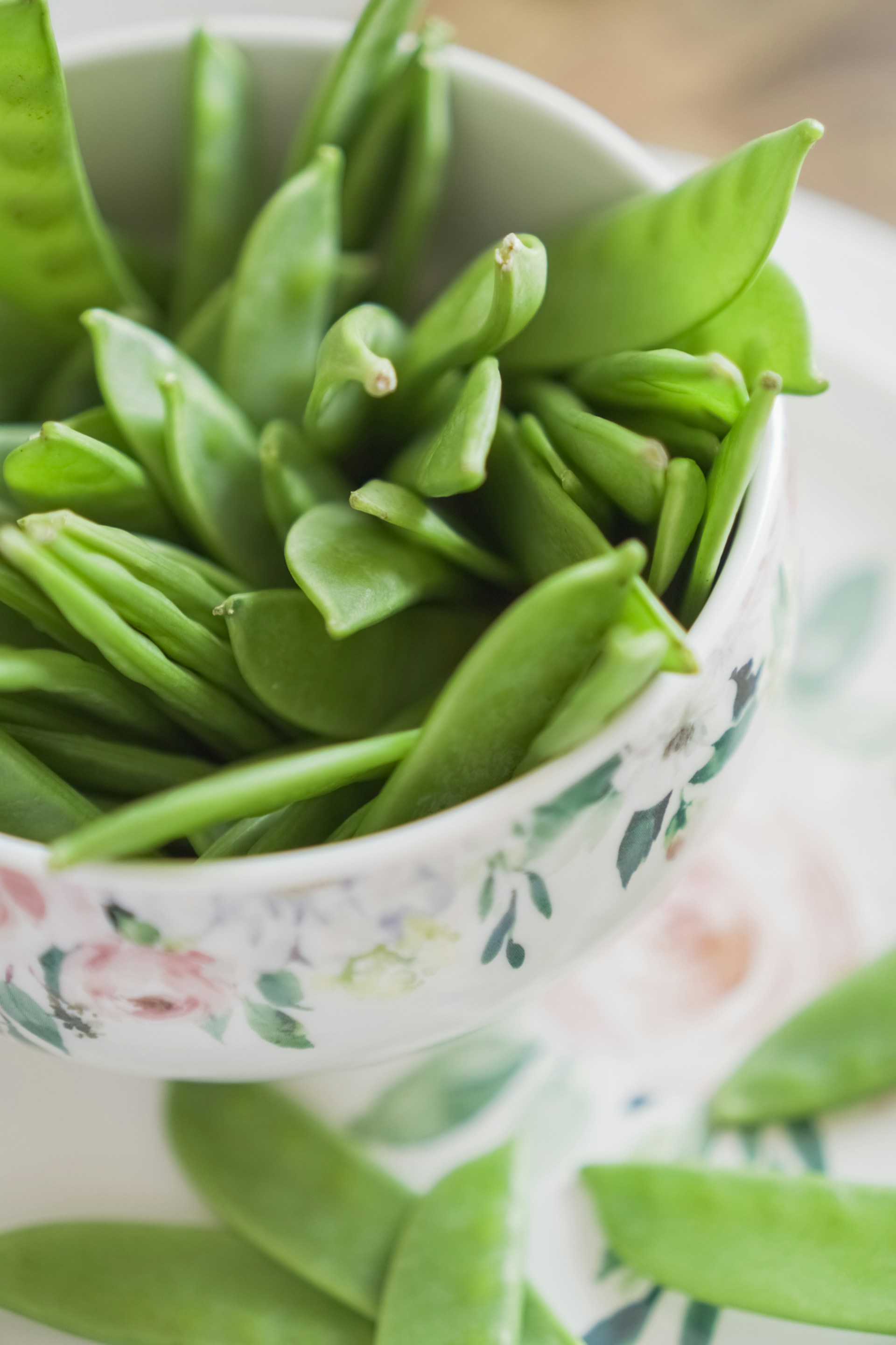 green beans sugar snap peas on a white floral bowl 